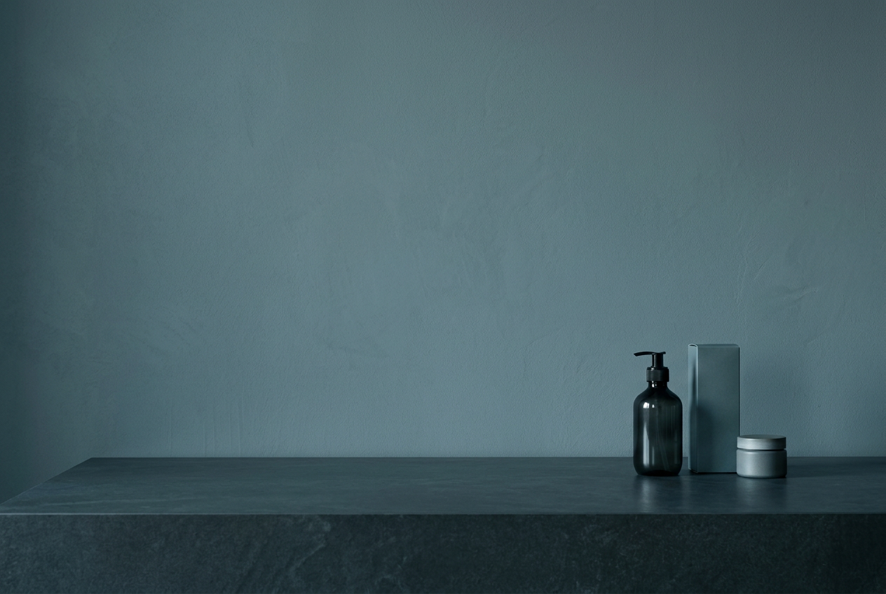 Three understated consumer products on a stone counter against a quiet blue-grey wall