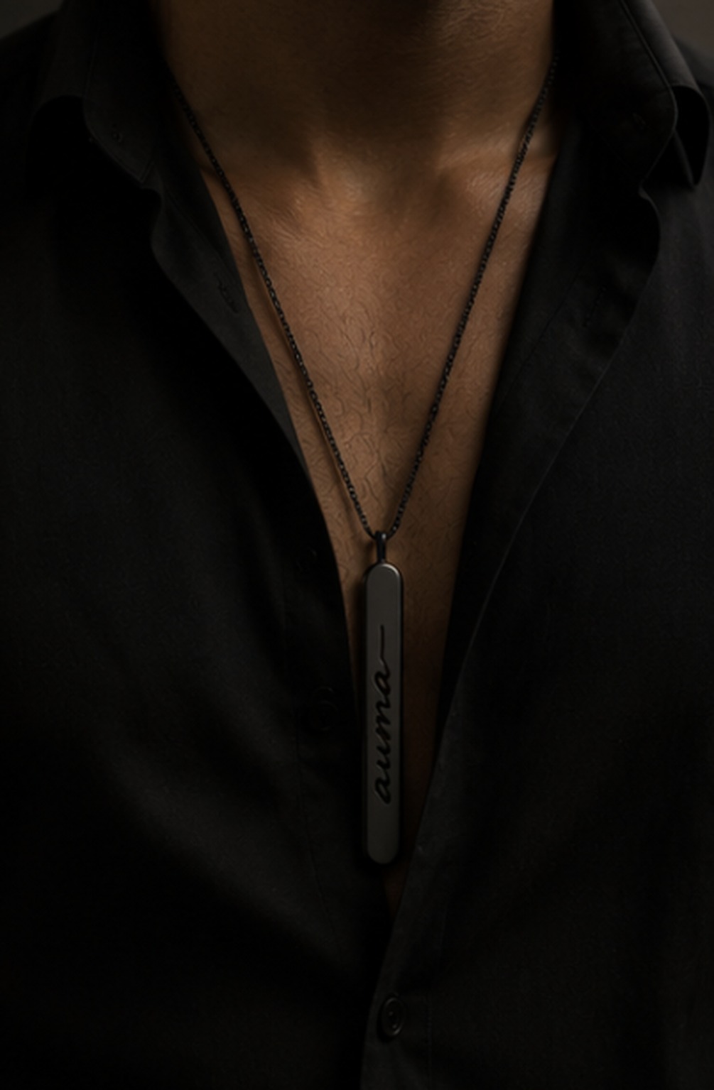 The black Auma scent pendant worn over an open black shirt